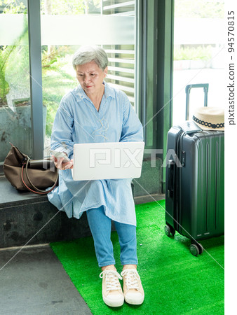 relax, vacation, travel, portrait of senior adult elderly asian woman 60s smiling using the computer laptop and smartphone while waiting for their travel time. relax, vacation, travel, portrait of senior adult elderly asian woman 60s smiling using the computer laptop and smartphone while waiting for their travel time. 94570815