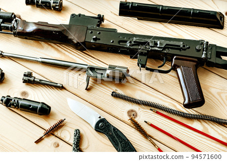 Disassembled rifle with cleaning tools on table of weapons workshop 94571600