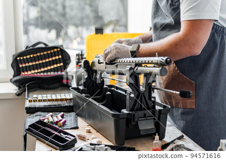 The gunsmith maintaining his rifle in a workshop The gunsmith maintaining his rifle in a workshop 94571616