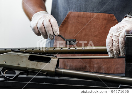 The gunsmith maintaining his rifle in a workshop The gunsmith maintaining his rifle in a workshop 94571696