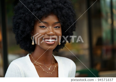 Portrait of young african woman with hairstyle smiling in urban background 94571837