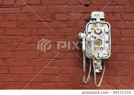 Old vintage telephone on a street brick wall. Steampunk technology, design, retro style concept. Old vintage telephone on a street brick wall. Steampunk technology, design, retro style concept. 94572158