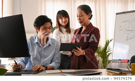 Smiling senior business leader negotiating growth business plan with young employees at meeting Smiling senior business leader negotiating growth business plan with young employees at meeting 94574374