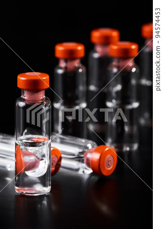 Close-up of medicine for injection in glass vials on a dark background Close-up of medicine for injection in glass vials on a dark background 94574453