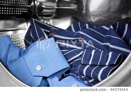 Close-up of an open door in washing machine with dirty shirts inside Close-up of an open door in washing machine with dirty shirts inside 94574454