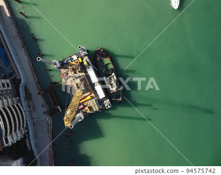 Floating crane dredging barges working on the construction of a marina. Aerial top view Floating crane dredging barges working on the construction of a marina. Aerial top view 94575742