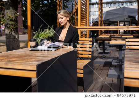 young business woman sitting in a cafe with a laptop diary 94575971