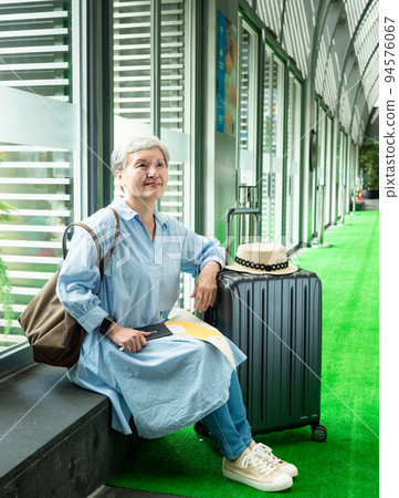 休閒、度假、旅行,60歲的亞洲女性面帶微笑,坐在手提包裡,提著包等,等待著旅行的時間。 休閒、度假、旅行,60歲的亞洲女性面帶微笑,坐在手提包裡,提著包等,等待著旅行的時間。 94576067