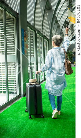 60歲亞洲老太婆畫像，面帶微笑，駐紮，手提箱，手持旗桿，靈活的旅行樂隊概念。 94576103