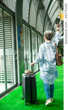 60歲亞洲老太婆畫像，面帶微笑，駐紮，手提箱，手持旗桿，靈活的旅行樂隊概念。 94576108