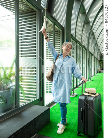 60-year-old Asian portrait of old and old women, smiling, stationed, hand-carried box, hand-held flag pole, flexible travel band concept. 60-year-old Asian portrait of old and old women, smiling, stationed, hand-carried box, hand-held flag pole, flexible travel band concept. 94576127