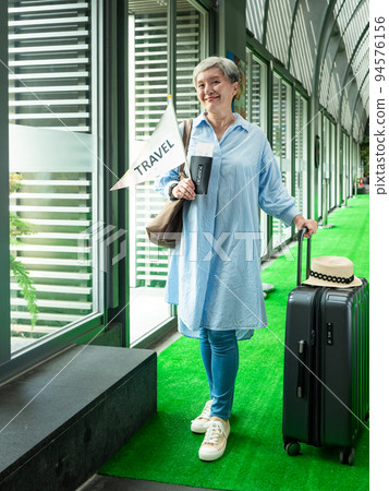 60歲亞洲老太婆畫像,面帶微笑,駐紮,手提箱,手持旗桿,靈活的旅行樂隊概念。 60歲亞洲老太婆畫像,面帶微笑,駐紮,手提箱,手持旗桿,靈活的旅行樂隊概念。 94576156