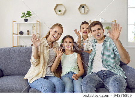 Young family with two children wave their hands in front of web camera to greet their relatives. Young family with two children wave their hands in front of web camera to greet their relatives. 94576899
