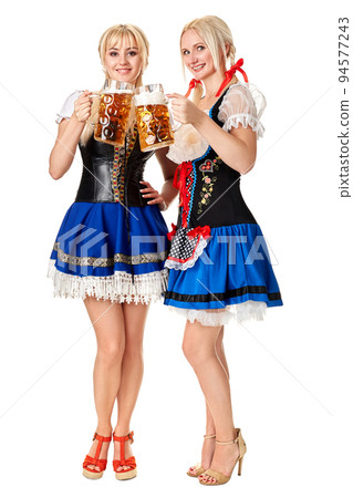 Full length portrait of a two blond womans with traditional costume holding beer glasses isolated on white background. 94577243