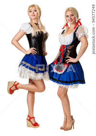A full length portrait of two beautiful women in a traditional costume isolated on white. Oktoberfest A full length portrait of two beautiful women in a traditional costume isolated on white. Oktoberfest 94577249