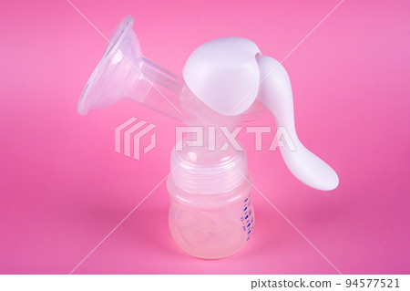 Manual breast pump on pink paper background. Device for increasing milk supply for breastfeeding mother. Maternity and baby care concept Manual breast pump on pink paper background. Device for increasing milk supply for breastfeeding mother. Maternity and baby care concept 94577521