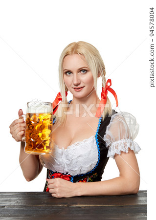 Young bavarian woman in dirndl sitting at table with beer on white background Young bavarian woman in dirndl sitting at table with beer on white background 94578004