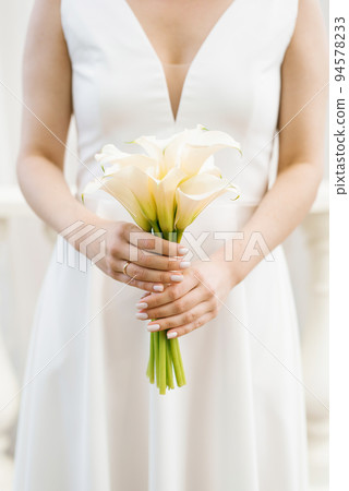 White bridal bouquet of calla lilies in the hands of the bride 94578233