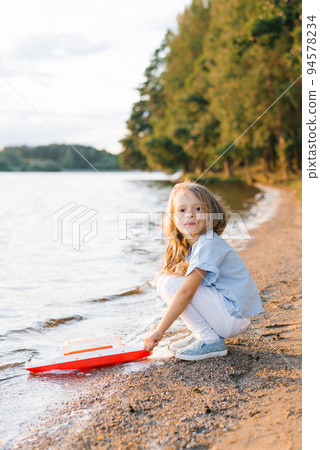 A girl launches a boat into the lake 94578234
