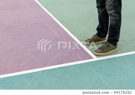 Men feet stand on the rubberized sports playground painted in pastel colors 94578282
