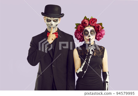 Couple in Halloween costumes put fingers to lips asking you to be silent and keep secret 94579995