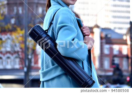 A young office worker carrying an adjuster case and walking in the office district 94580508