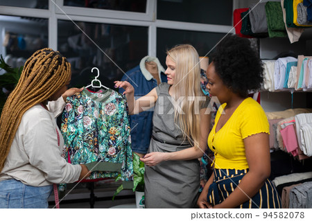 A European woman looks at a blouse in shades of green in a tailor's workshop. A European woman looks at a blouse in shades of green in a tailor's workshop. 94582078