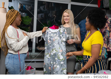 A dark-skinned saleswoman offers a customer a new dress for the summer. A dark-skinned saleswoman offers a customer a new dress for the summer. 94582082