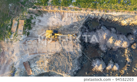 Yellow tracked bulldozer performs earthworks - aerial view shot. Yellow tracked tractor rakes the Yellow tracked bulldozer performs earthworks - aerial view shot. Yellow tracked tractor rakes the 94582203