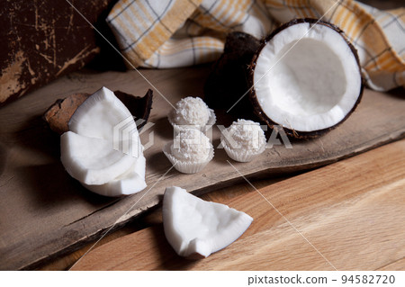 Coconut with white pulp and white candies on wooden background.. 94582720