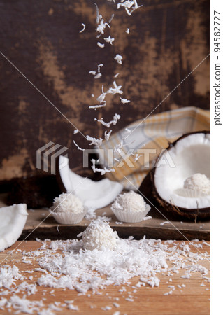 Close up of white candies and coconut with white pulp, coconut chip on wooden background.. Close up of white candies and coconut with white pulp, coconut chip on wooden background.. 94582727