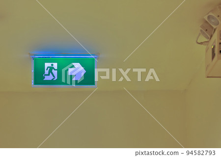 Green emergency exit sign showing the way to escape. Fire exit in the building. Green emergency exit sign showing the way to escape. Fire exit in the building. 94582793