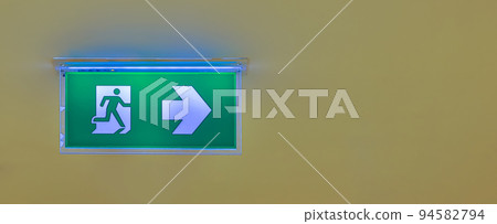 Green emergency exit sign showing the way to escape. Fire exit in the building. Green emergency exit sign showing the way to escape. Fire exit in the building. 94582794