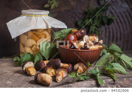 Pile of Imleria Badia or Boletus badius mushrooms commonly known as the bay bolete with canned mushroom in glass jar on vintage wooden background.. Pile of Imleria Badia or Boletus badius mushrooms commonly known as the bay bolete with canned mushroom in glass jar on vintage wooden background.. 94582806