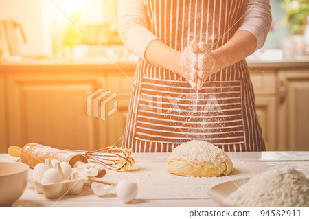 Woman slap his hands above dough closeup. Baker finishing his bakery, shake flour from his hands, free space for text. 94582911