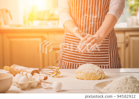 Woman slap his hands above dough closeup. Baker finishing his bakery, shake flour from his hands, free space for text. Woman slap his hands above dough closeup. Baker finishing his bakery, shake flour from his hands, free space for text. 94582912