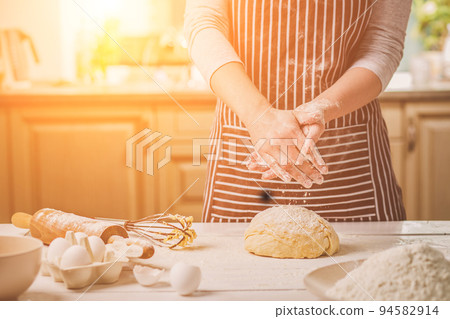 Woman slap his hands above dough closeup. Baker finishing his bakery, shake flour from his hands, free space for text. Woman slap his hands above dough closeup. Baker finishing his bakery, shake flour from his hands, free space for text. 94582914