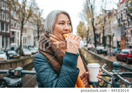Senior woman have a breakfast in amsterdam with coffee and croissant 94583014
