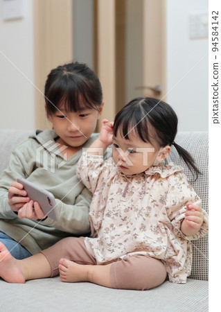 Sister girls playing with smartphones 94584142