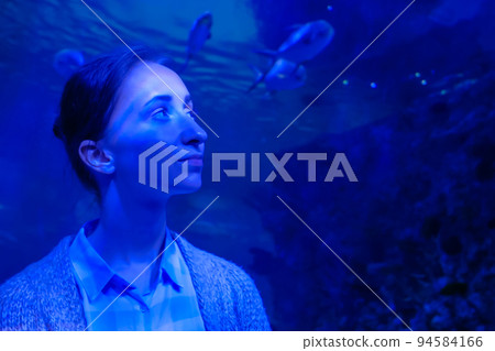 Woman looking at fish in large public aquarium tank at oceanarium 94584166