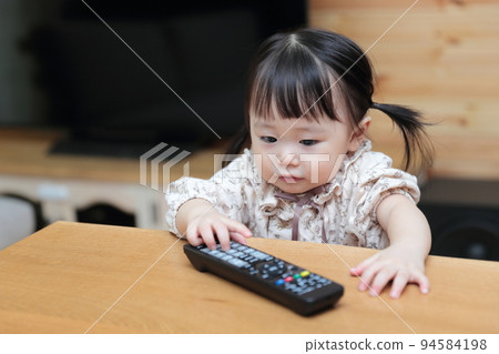 1歲小女孩在玩電視遙控器 94584198