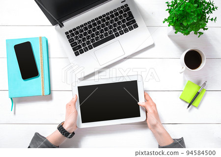 Hand use white tablet on desk table top view 94584500