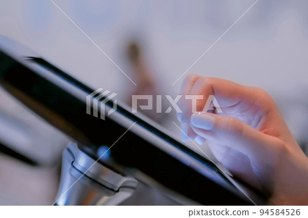 Woman hand using touchscreen display of floor standing black tablet kiosk Woman hand using touchscreen display of floor standing black tablet kiosk 94584526