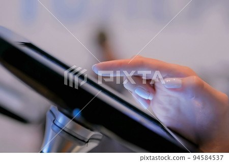 Woman hand using touchscreen display of floor standing black tablet kiosk Woman hand using touchscreen display of floor standing black tablet kiosk 94584537