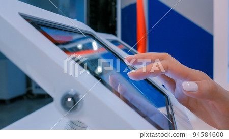 Woman hand using touchscreen display of floor standing white tablet kiosk Woman hand using touchscreen display of floor standing white tablet kiosk 94584600