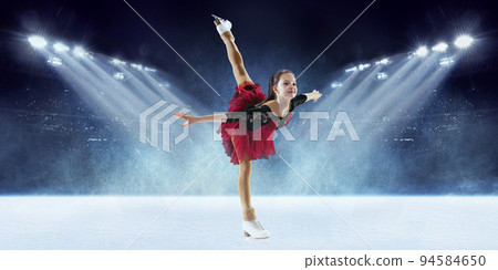 Beautiful female beginner figure skater in stage dress skating at ice arena with spotlights. Dance, winter sports, achievements, champion concept 94584650