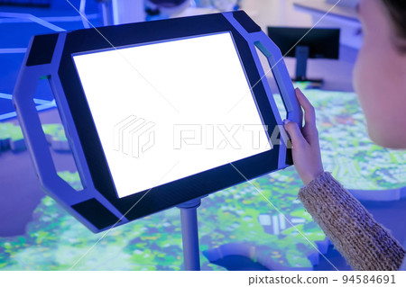 Close up view: woman using floor standing tablet kiosk with blank white display 94584691