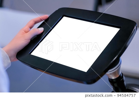 Close up view: woman using floor standing tablet kiosk with blank white display 94584757