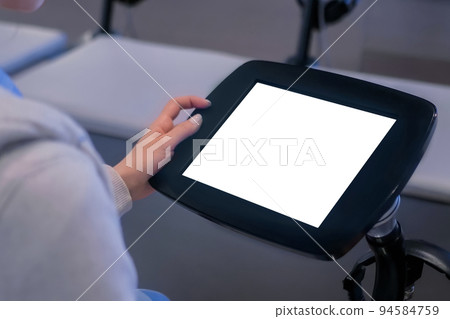 Woman looking at floor standing black tablet kiosk with blank white display Woman looking at floor standing black tablet kiosk with blank white display 94584759