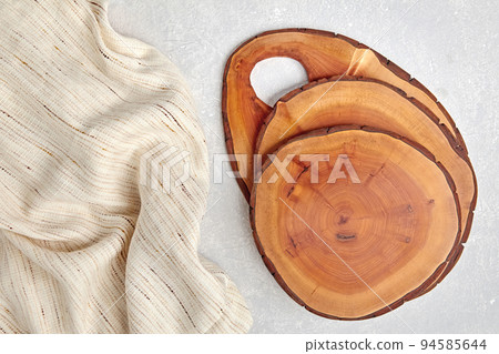 Wooden cutting boards or do-it-yourself food plate coasters on a light concrete table and kitchen towel with copy space 94585644